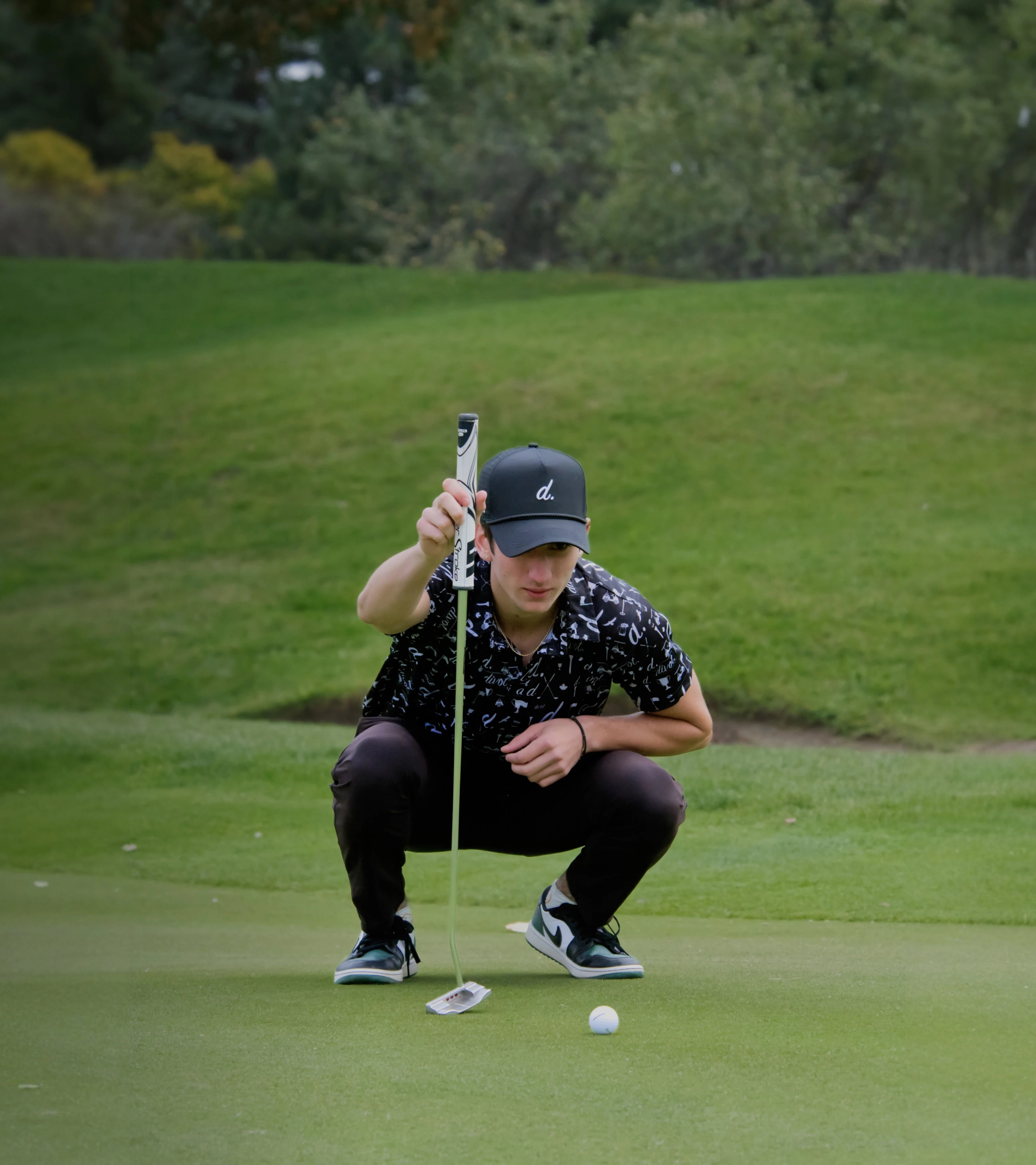 Nico on a golf course preparing to putt with a golf ball and club.
