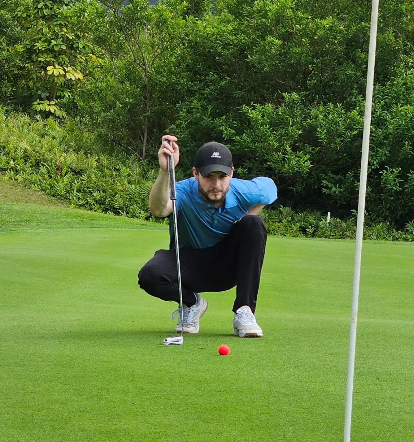 Yeti preparing to putt on a golf course with greenery in the background